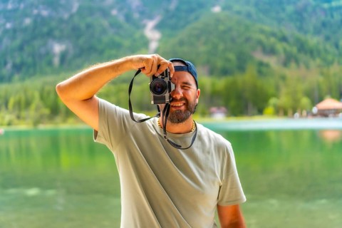 Tourist taking pictures with vintage camera at lake dobbiaco, surrounded by the breathtaking