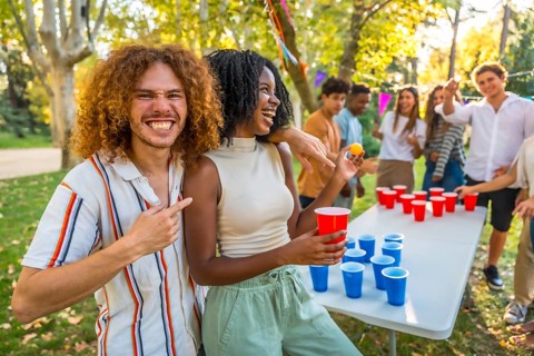 Man pointing at a female african friend that wins playing beer pong at park