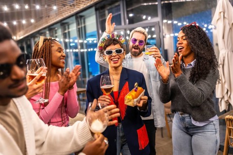 Happy woman celebrating birthday with multiracial friends at bar in the night