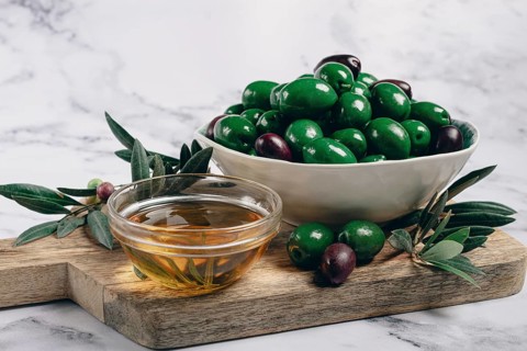 Chalkidiki olives, classic Greek green olives, in a bowl on a cutting board, top view, without
