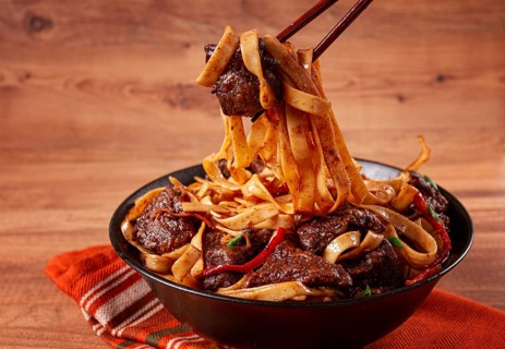 Udon noodles with beef in Mongolian style, with green onions and vegetables, served in a black