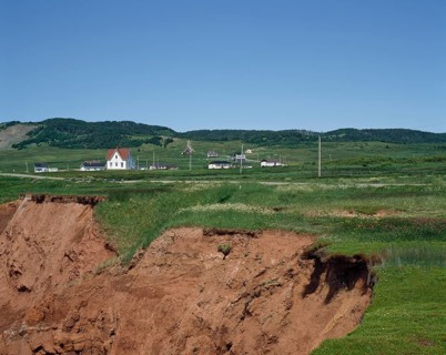 Cliff with eroded soil and houses in the distance in summer, Havre-Aubert, Magdalen Islands,