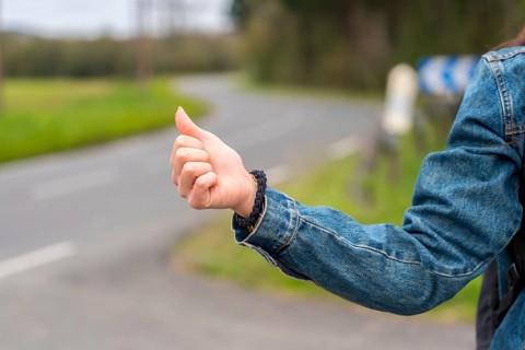 Close-up photo of the hand of a woman hitchhiking in a rural road