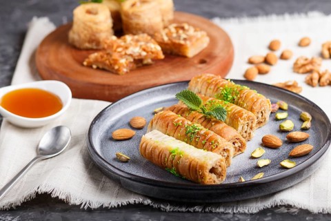 Set of various traditional arabic sweets: baklava, kunafa, basbus in ceramic plates on a gray