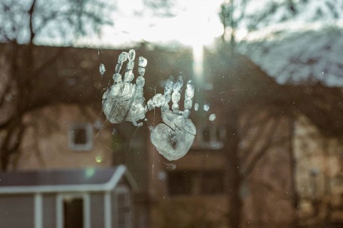 Fingerprints on a window in sunlight with houses in the background