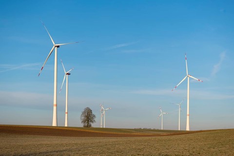 Several wind turbines rotating over a wide field, sustainable energy generation shown, solar park,