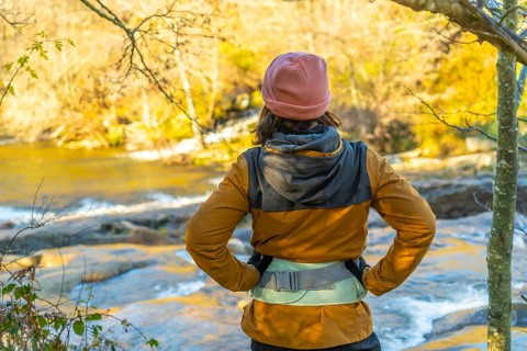 Hiker admiring the serene zaldibartxo pool in gorbeia natural park on a sunny autumn day,