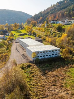 Industrial building on a hill with autumnal trees in a village, refugee accommodation Beermiß,