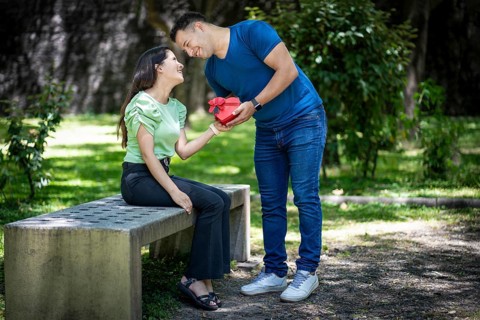 Latin couple in love in a park with a heart-shaped gift in their hands