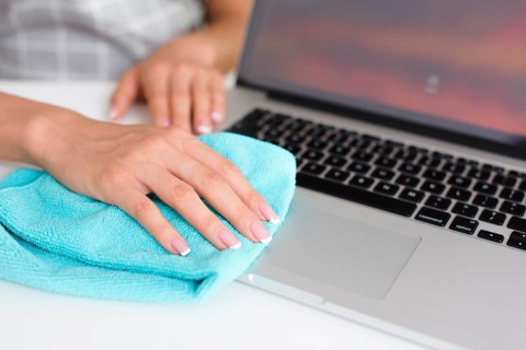 Woman hand cleaning laptop home
