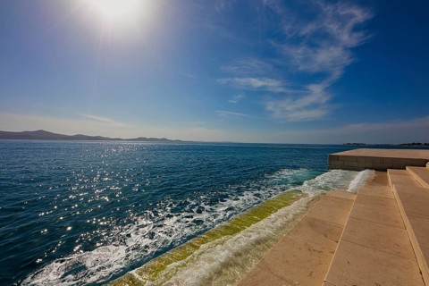 Steps lead to the clear sea under bright sunshine and blue sky, a calm coastal atmosphere, sea