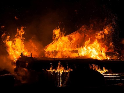Arson or nature disaster, burning fire flame on wooden house roof