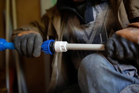 Close-up of gloved hands adjusting a pipe fitting