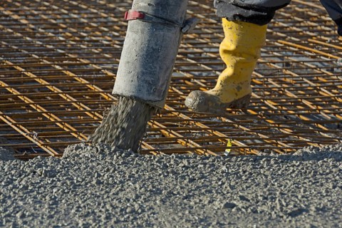 Construction worker pours concrete onto reinforcing steel using a concrete pump