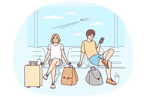 Happy couple with suitcases sitting in airport ready for summer vacation. Smiling man and woman