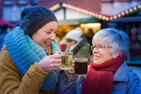 Two woman standing at the Christmas market drinking mulled wine