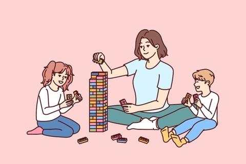Woman babysitter together with kids plays constructor building tower of children blocks in