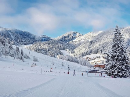 Picturesque snowy mountain landscape with slopes, lifts, and skiers at La Clusaz ski resort,