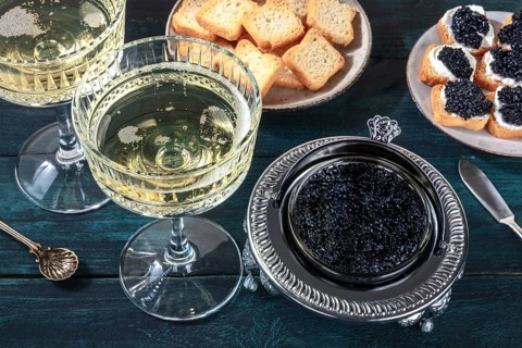 Caviar and champagne, vintage style, with bread and toasts on a dark blue wooden background