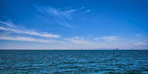Panoramic beautiful seascape on a bright summer day with few sailing boats afar, great sky with