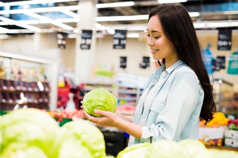 Smiling asian woman choosing cabbage market