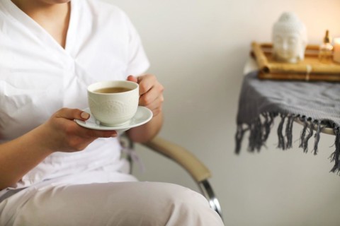 Cropped photo of happy lovely young female health worker laughing sincerely while holding cup of