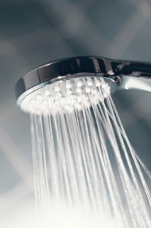 Shower head with flow of water spilling out closeup. Modern shower head splashing water close up