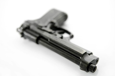 Black hand gun pistol over white background, selective focus, studio shot