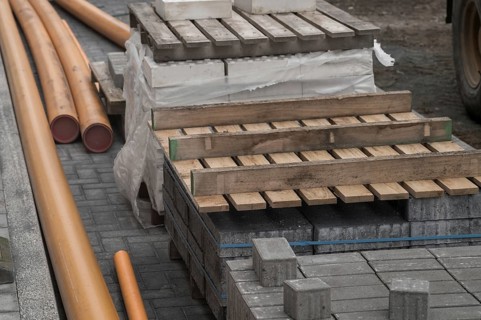 Construction materials including paving stones, orange pipes and wooden pallets laying on a