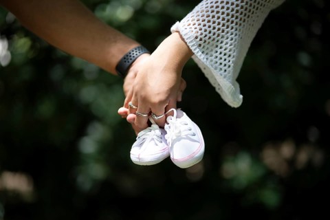 Detail of a couple's hands holding baby shoes