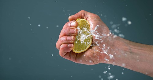 Hand of Man Squeezing Lemon, citrus limonum against Black Background