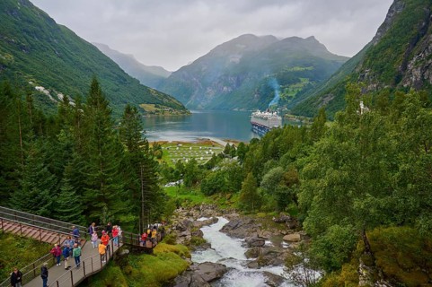 An impressive landscape with a raging waterfall, surrounded by green mountains and forests, with a