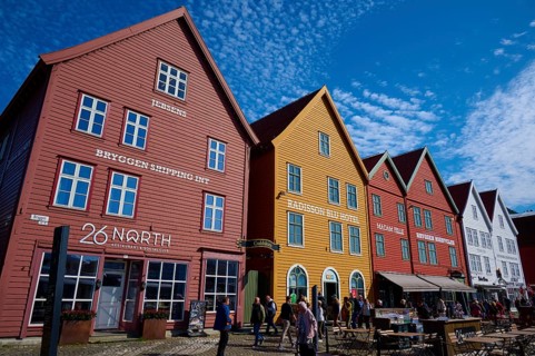 Traditional wooden houses under a blue sky with pitched roofs and multiple windows in a sunny old