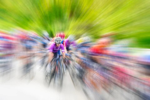 Cyclist in sportswear and helmet riding at high speed on a road, race, the motion blur emphasises