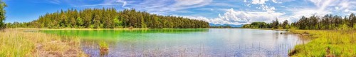 A panorama of a clear lake with vibrant colours and a surrounding forest, Osterseen