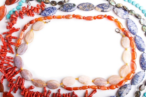 Frame of semiprecious stone beads on white background, top view