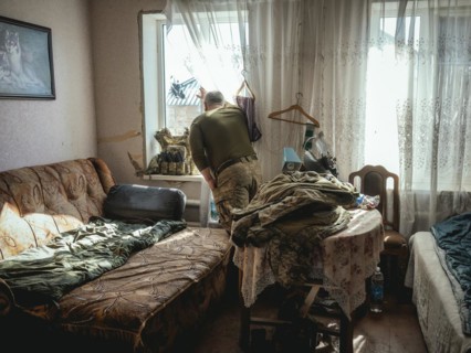 Gennady, 48 years old, stationed in Kupyansk, looking out of the window of the house where his unit
