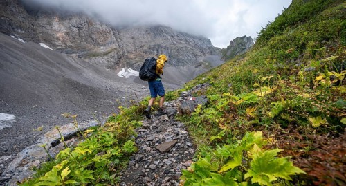 Mountaineer hiking in the mountains with yellow jacket, hiking trail to Valentintörl, cloudy