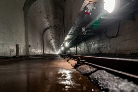 Deep tunnel with wet concrete walls and light at the end, industrial ambience, Rappbodetalsperre,