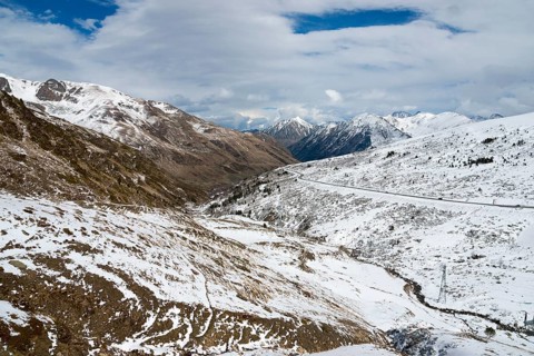Winterliche Landschaft in den schneebedeckten Bergen von Andorra mit einer Straße und Wolken am