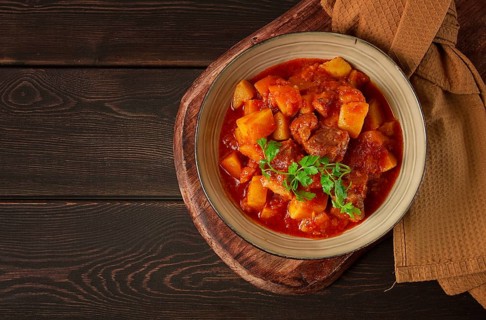 Stew with potatoes, in tomato sauce, with spices and herbs, close-up, no people, on a black