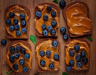 Rye bread with peanut paste and fresh blueberries, top view, no people