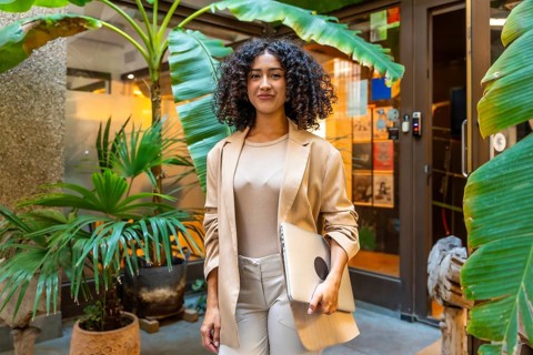 Three quarter length portrait of a beauty young businesswoman standing carrying a laptop next to