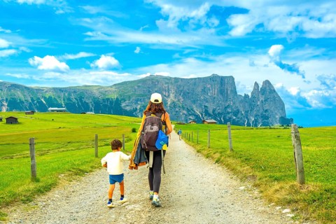 Mother and son enjoying a summer hike in the picturesque landscape of alpe di siusi, with the