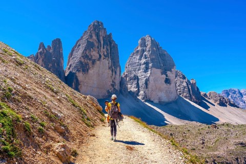 Tourists walking on a mountain path near tre cime di lavaredo, dolomites, a famous landmark in
