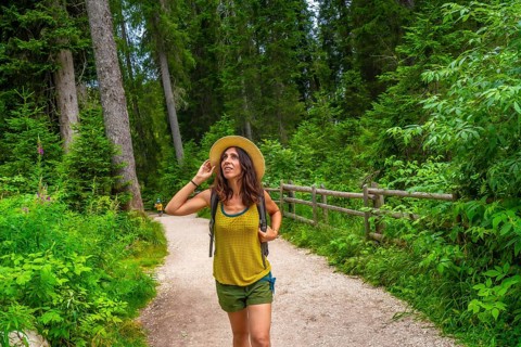 Female tourist enjoying a walk along a forest trail near lake carezza in the italian dolomites