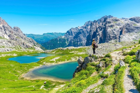 Hiker enjoying the breathtaking view of the tre cime di lavaredo peaks and the turquoise alpine