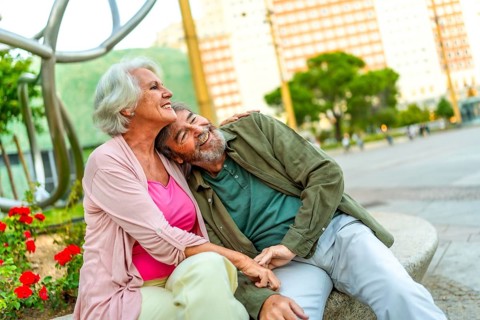 Mature couple sitting together in an urban bench contemplating the city views from the square