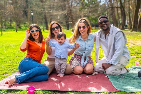 Cheerful multi ethnic friends enjoying a fun picnic in the park, laughing and bonding together with