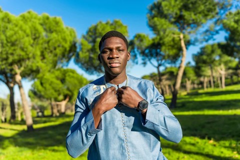 Young senegalese man wearing traditional dashiki attire, posing in a serene park setting,